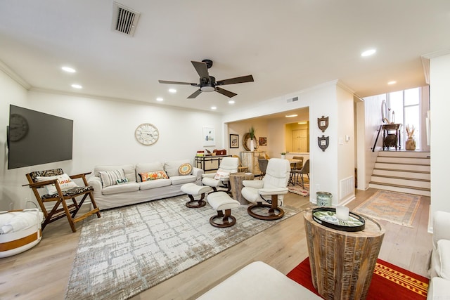 living room featuring ceiling fan, crown molding, and light wood-type flooring