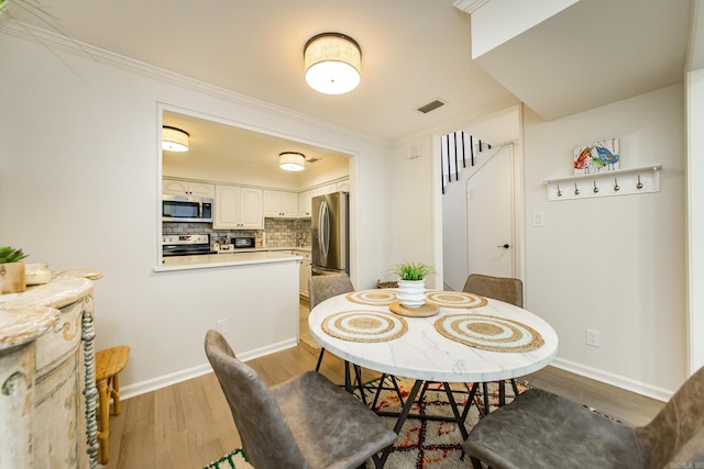 dining room featuring light wood-type flooring and ornamental molding