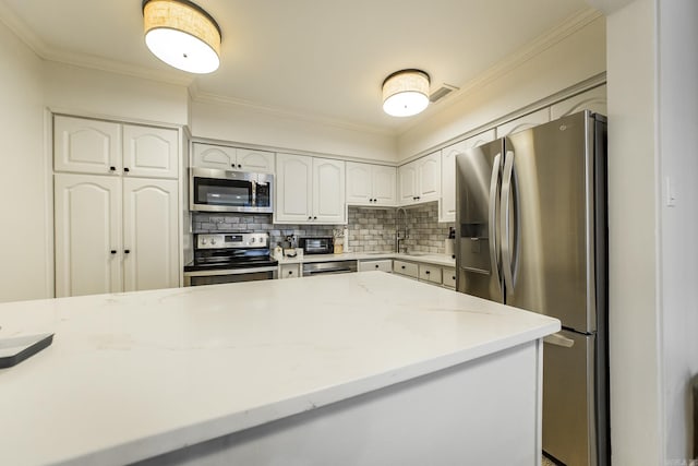 kitchen with white cabinets, decorative backsplash, ornamental molding, appliances with stainless steel finishes, and light stone counters