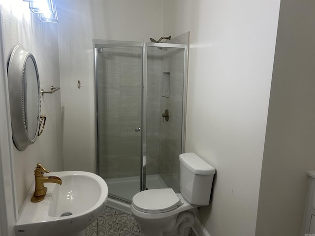 bathroom with toilet, a shower with door, and sink