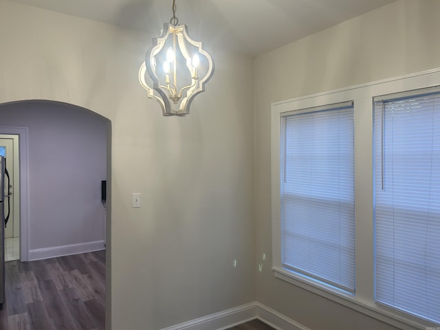 unfurnished dining area with dark hardwood / wood-style flooring and a chandelier