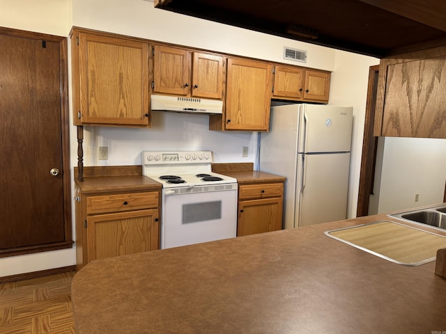 kitchen featuring white appliances, dark parquet floors, and sink