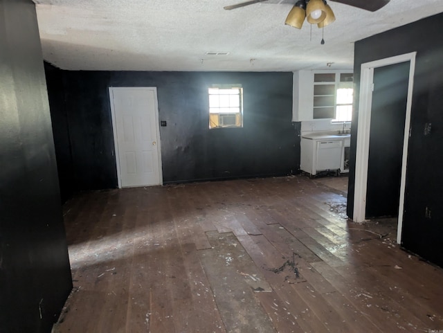 interior space featuring ceiling fan, cooling unit, dark hardwood / wood-style floors, and a textured ceiling