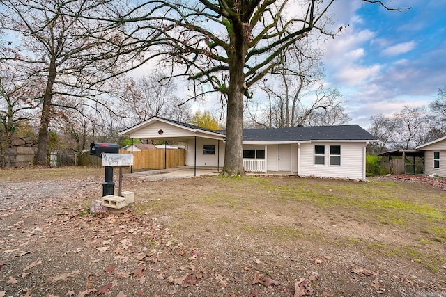 single story home featuring a carport, a porch, and a front yard