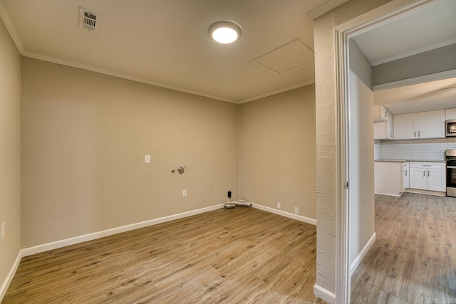 empty room with crown molding and light hardwood / wood-style floors