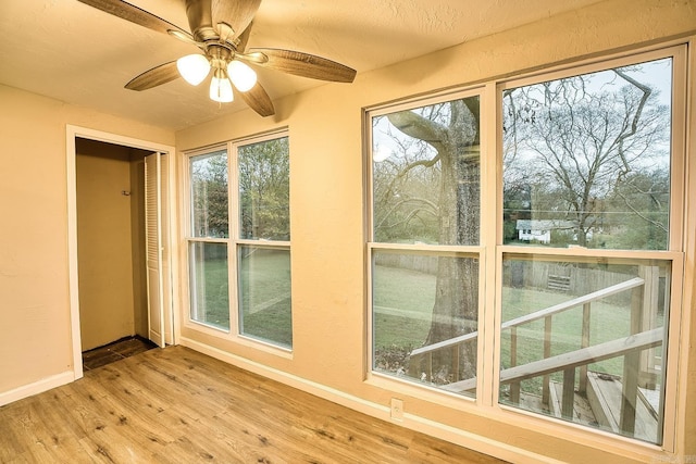 unfurnished sunroom featuring ceiling fan