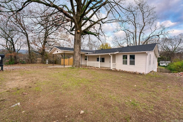 view of front of home with covered porch, a front yard, and a carport