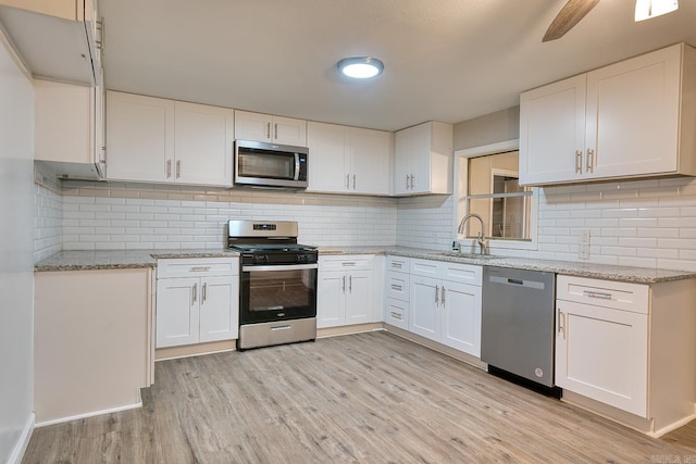 kitchen featuring light wood-type flooring, backsplash, stainless steel appliances, sink, and white cabinets