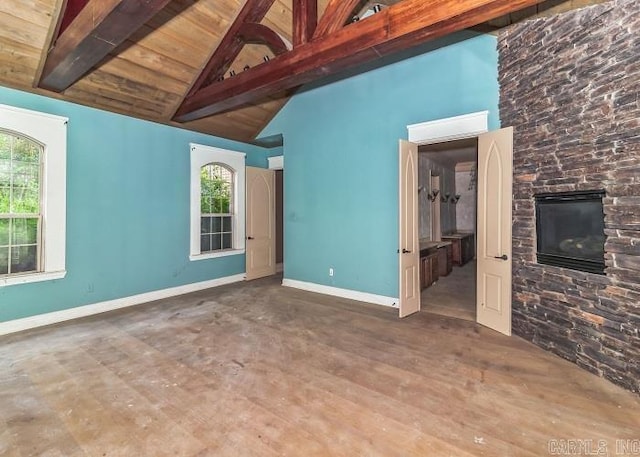 unfurnished living room with dark hardwood / wood-style flooring, beam ceiling, high vaulted ceiling, wooden ceiling, and a stone fireplace