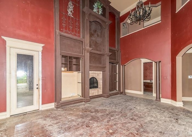 unfurnished living room with a towering ceiling and a tiled fireplace