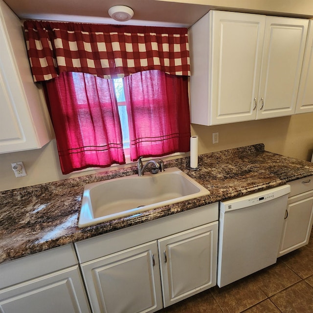 kitchen featuring dark stone counters, white dishwasher, sink, dark tile patterned flooring, and white cabinets