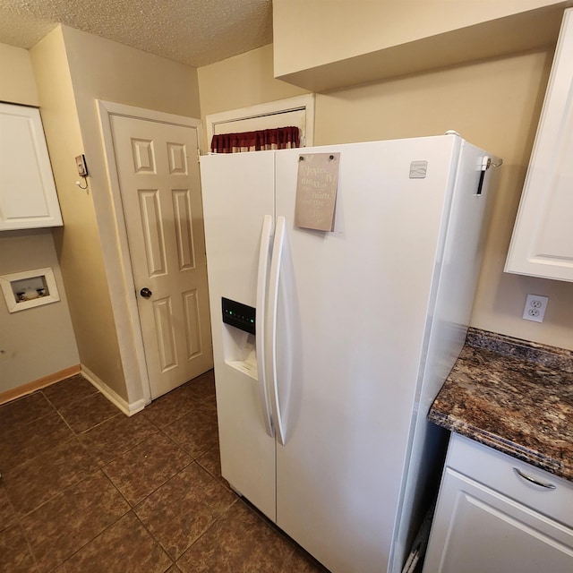 kitchen featuring a textured ceiling, dark stone countertops, white cabinets, and white refrigerator with ice dispenser