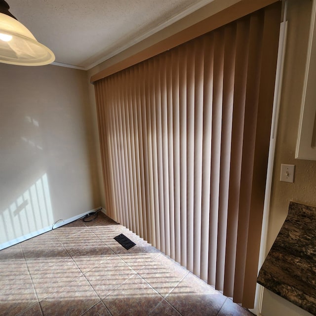 unfurnished bedroom with tile patterned flooring, a textured ceiling, and ornamental molding