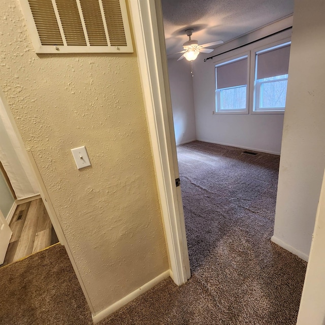 corridor featuring carpet flooring and a textured ceiling