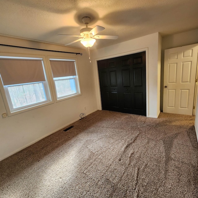 unfurnished bedroom featuring ceiling fan, a closet, carpet floors, and a textured ceiling