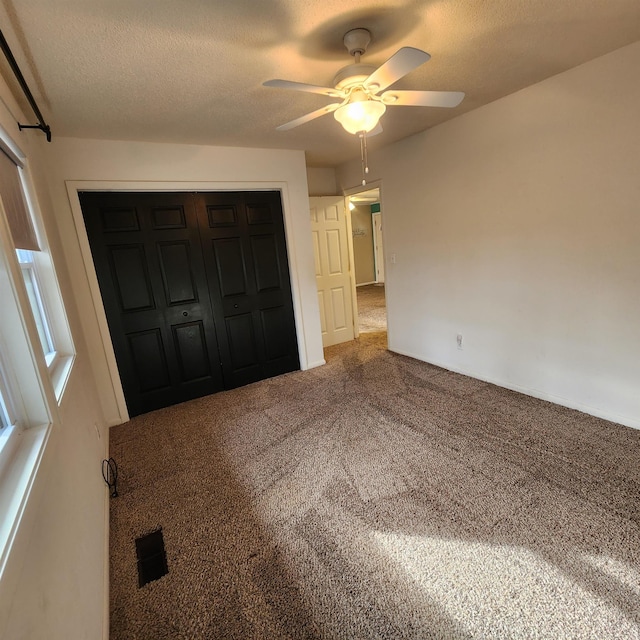 unfurnished bedroom featuring carpet, ceiling fan, a textured ceiling, and a closet