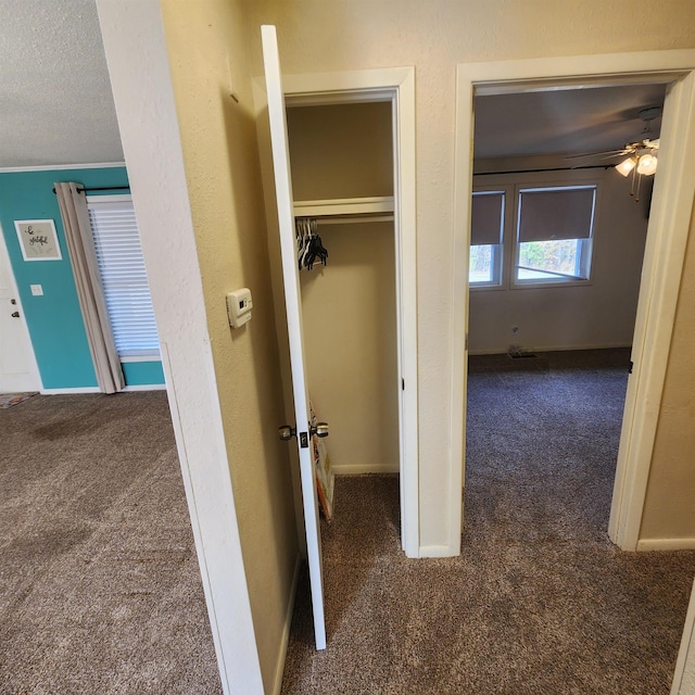 corridor with dark colored carpet and a textured ceiling