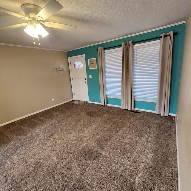 empty room with a textured ceiling, carpet floors, ceiling fan, and ornamental molding