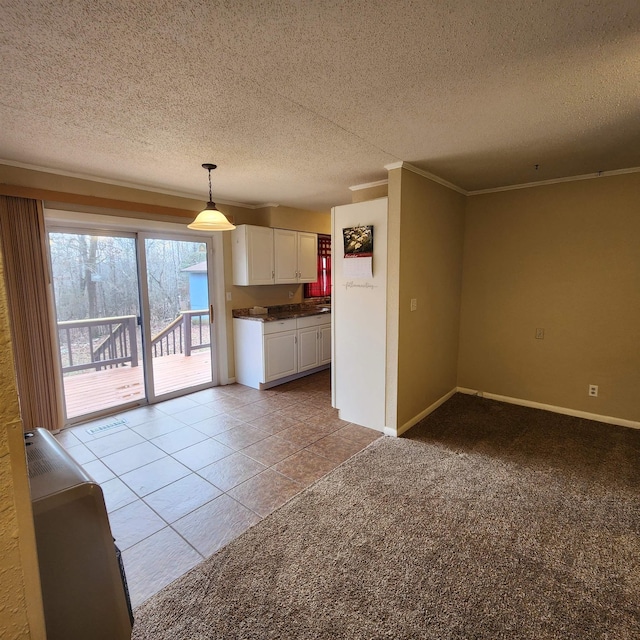 kitchen featuring a textured ceiling, light colored carpet, crown molding, white cabinets, and hanging light fixtures