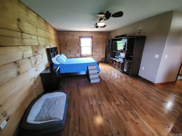 bedroom featuring ceiling fan, wood walls, and dark wood-type flooring