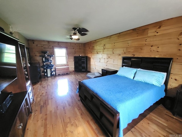 unfurnished bedroom with ceiling fan, wooden walls, and light hardwood / wood-style flooring