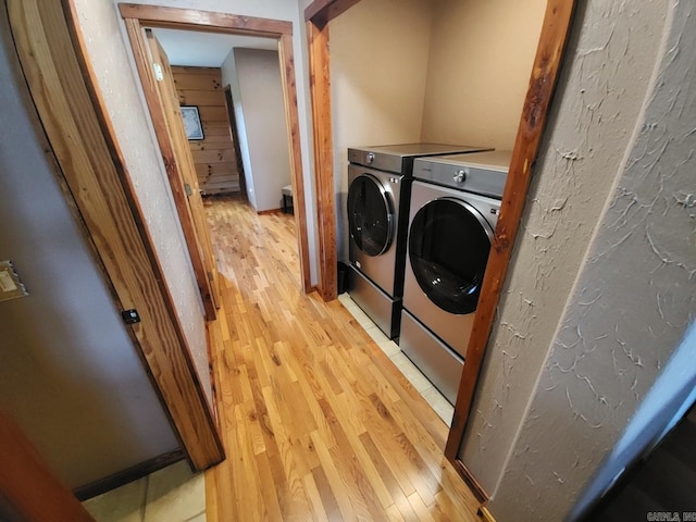 laundry room with washer and clothes dryer and light hardwood / wood-style flooring