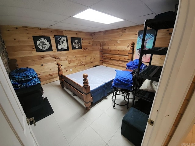 bedroom featuring a drop ceiling and wooden walls