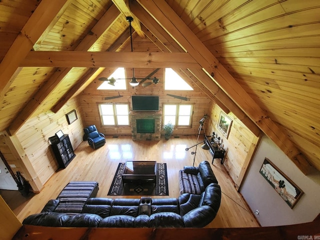 living room featuring a stone fireplace, hardwood / wood-style floors, beamed ceiling, and wood ceiling