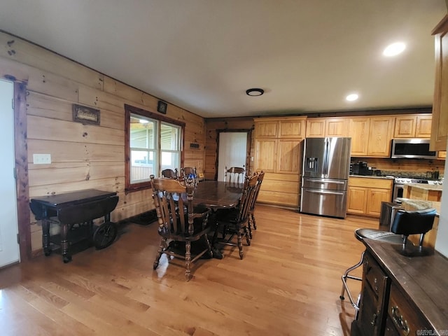 dining area featuring light wood-type flooring and wood walls