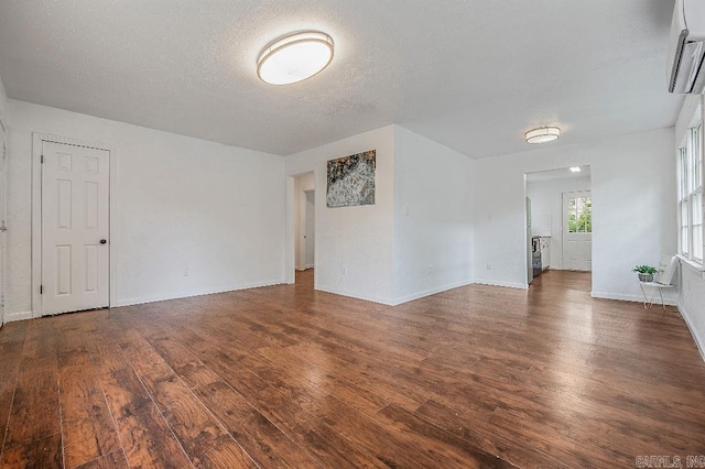 spare room with a wall unit AC, dark hardwood / wood-style flooring, and a textured ceiling