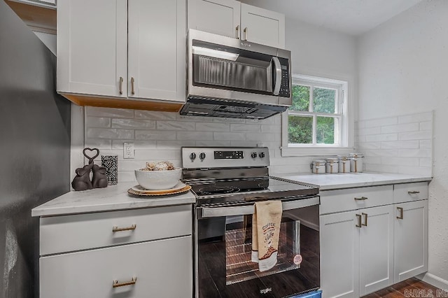 kitchen featuring white cabinets, appliances with stainless steel finishes, backsplash, dark hardwood / wood-style floors, and light stone counters