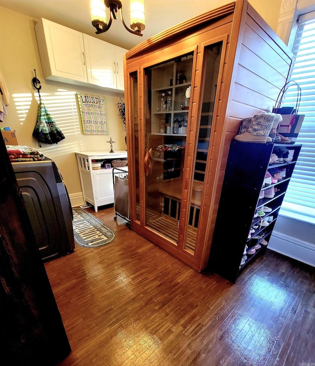 interior space with white cabinets, dark hardwood / wood-style floors, washer / dryer, and a chandelier