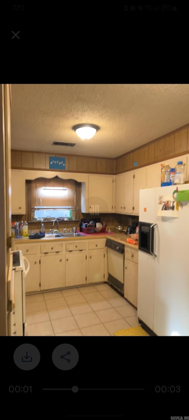 kitchen with white appliances, sink, a textured ceiling, and light tile patterned floors