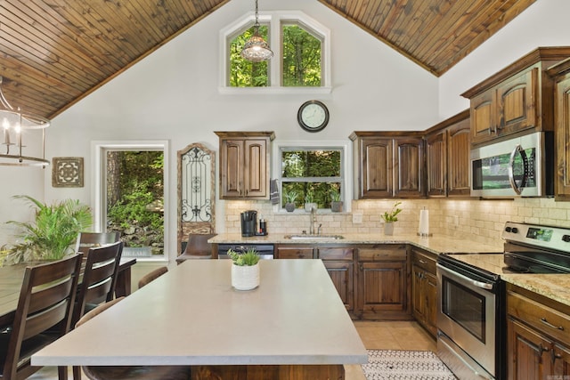 kitchen with pendant lighting, high vaulted ceiling, stainless steel appliances, and sink