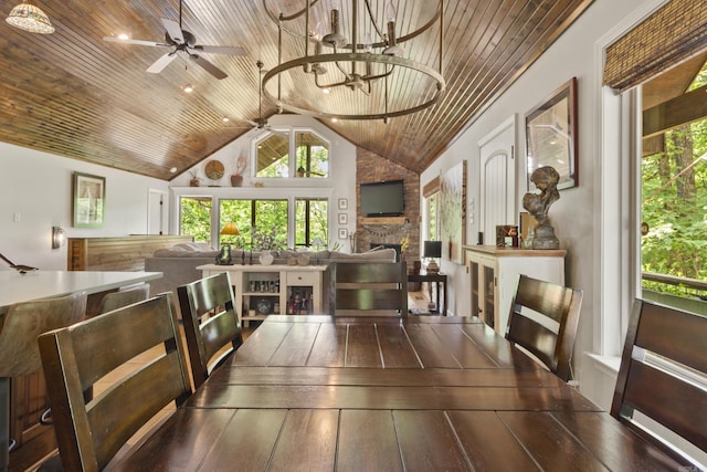 dining space featuring dark hardwood / wood-style flooring, a stone fireplace, a notable chandelier, and wood ceiling