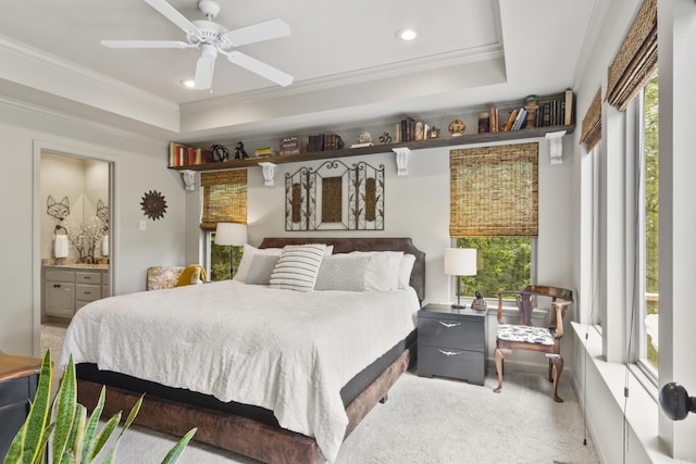 carpeted bedroom featuring ceiling fan, a raised ceiling, ornamental molding, and ensuite bath