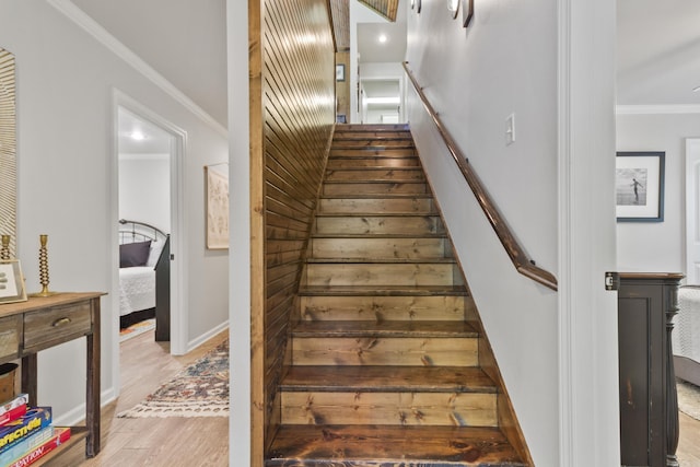 staircase with wood-type flooring and ornamental molding