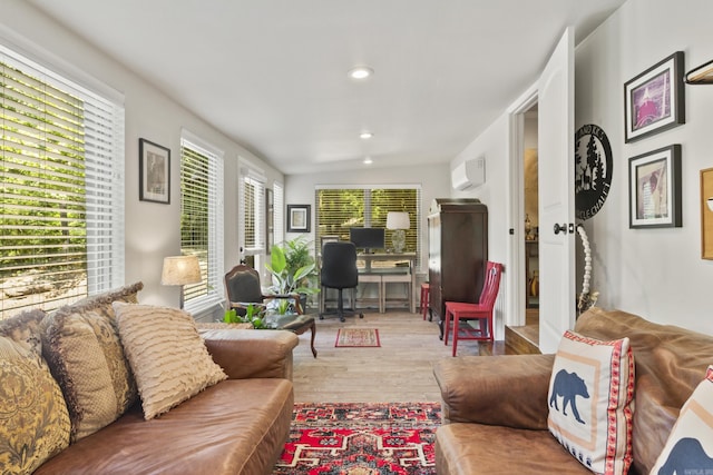 living room featuring an AC wall unit, plenty of natural light, and light hardwood / wood-style flooring