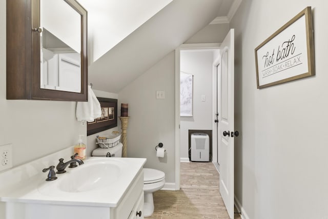 bathroom featuring toilet, hardwood / wood-style floors, vanity, and vaulted ceiling