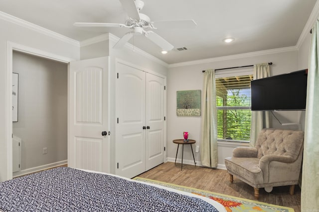 bedroom featuring hardwood / wood-style floors, ceiling fan, crown molding, and a closet