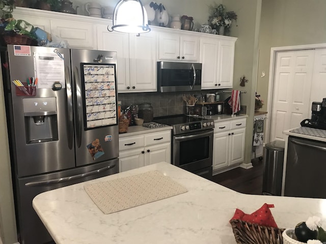 kitchen with white cabinets, light stone countertops, backsplash, and appliances with stainless steel finishes