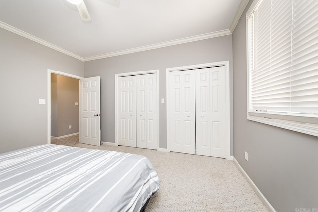 bedroom featuring two closets, light colored carpet, ceiling fan, and crown molding