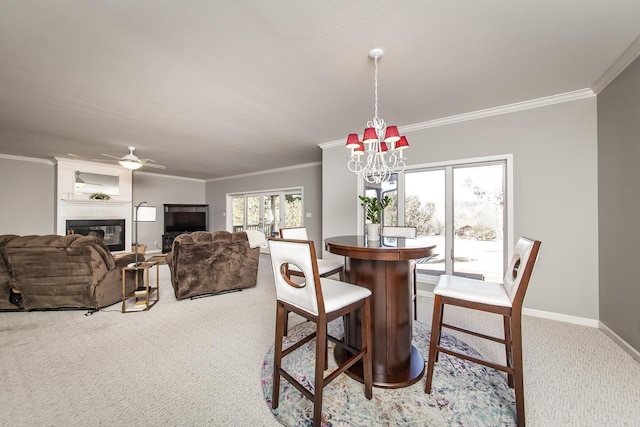 dining room with light carpet, a fireplace, crown molding, and ceiling fan with notable chandelier