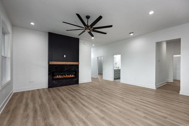 unfurnished living room featuring a premium fireplace, ceiling fan, and light hardwood / wood-style floors