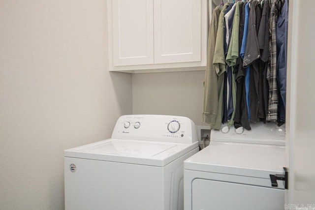 clothes washing area with cabinets and washing machine and dryer