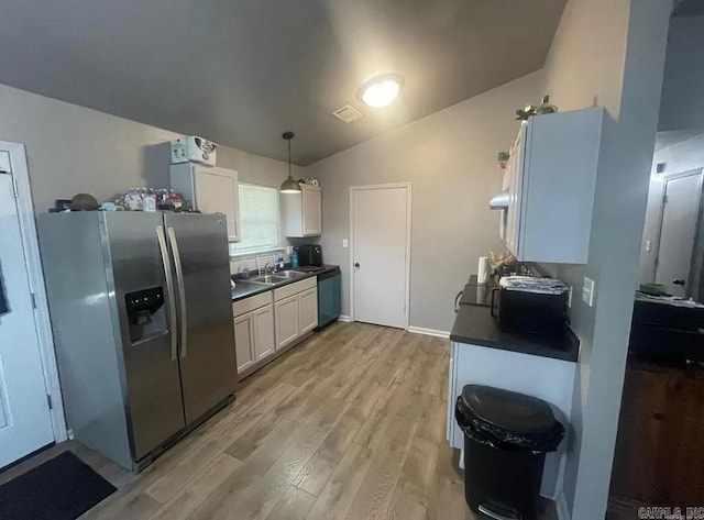 kitchen featuring pendant lighting, vaulted ceiling, stainless steel fridge with ice dispenser, light hardwood / wood-style floors, and white cabinetry