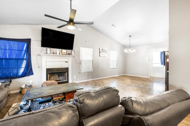 living room featuring vaulted ceiling, ceiling fan with notable chandelier, and hardwood / wood-style floors