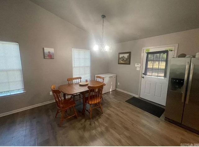 dining area with an inviting chandelier, vaulted ceiling, and dark hardwood / wood-style floors