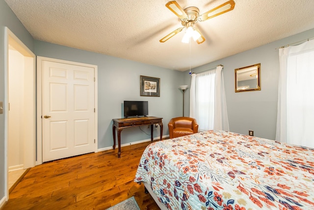 bedroom featuring ceiling fan, dark hardwood / wood-style flooring, and a textured ceiling