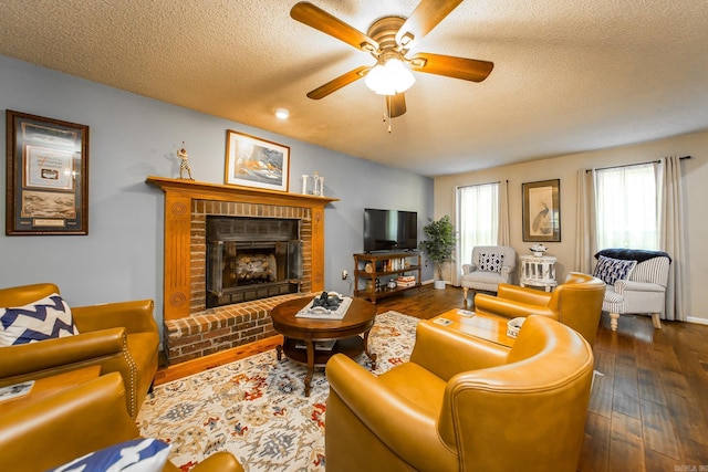 living room with a fireplace, ceiling fan, dark hardwood / wood-style flooring, and a textured ceiling